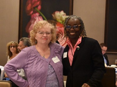  Two retirees smiling while photo taken at the Christiana Hilton Ballroom